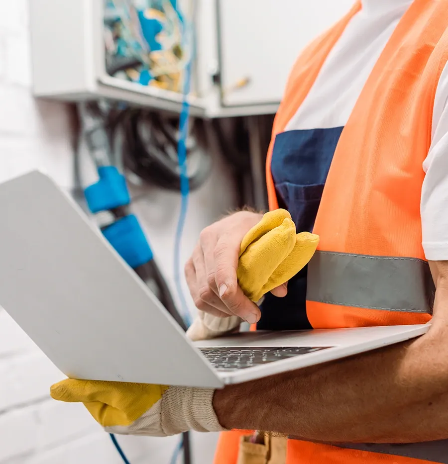 Contractor in a hi-vis vest checking figures on a laptop on site